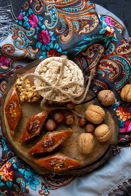 Free photo top view of traditional azerbaijani baklava with whole nuts and rice breads on a shawl with tassel