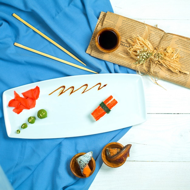 Top view of traditional japanese nigiri sushi with tuna served with soy sauce and ginger with wasabi on blue and white