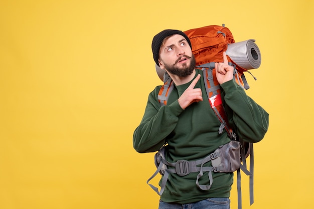 Free photo top view of travel concept with curious young guy with packpack and pointing up