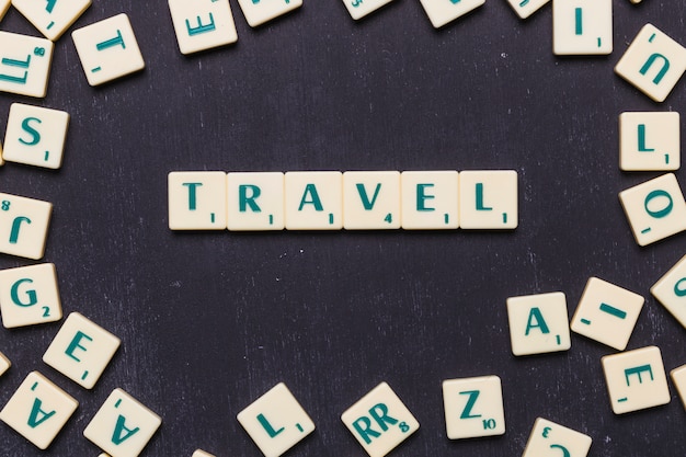 Free photo top view of travel text with scrabble letters over black backdrop