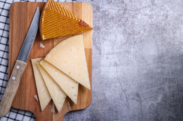 Free Photo top view of triangle pieces of cured manchego cheese and a sharp knife on a wooden food board