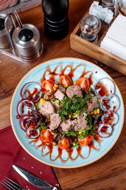 Top view of tuna salad with red onion and tomatoes on a plate