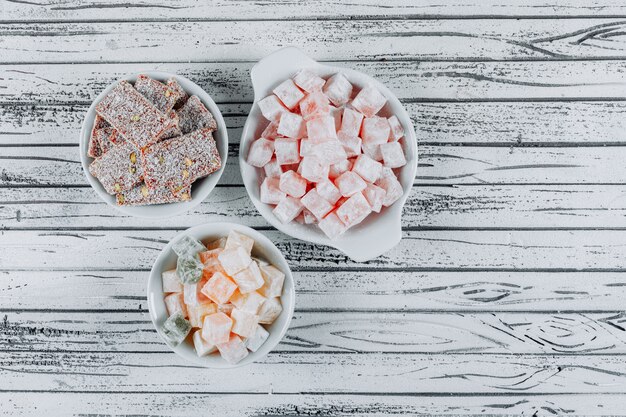 Top view turkish delight lokums in bowls on white wooden background. horizontal