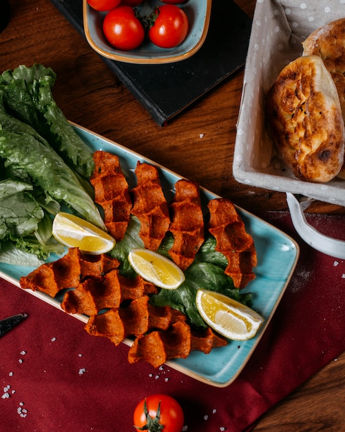 Free photo top view of turkish food cig kofte with lemon and lettuce on a wooden table