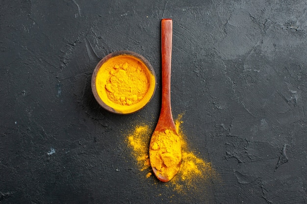 Free Photo top view turmeric bowl turmeric in wooden spoon on dark table free space