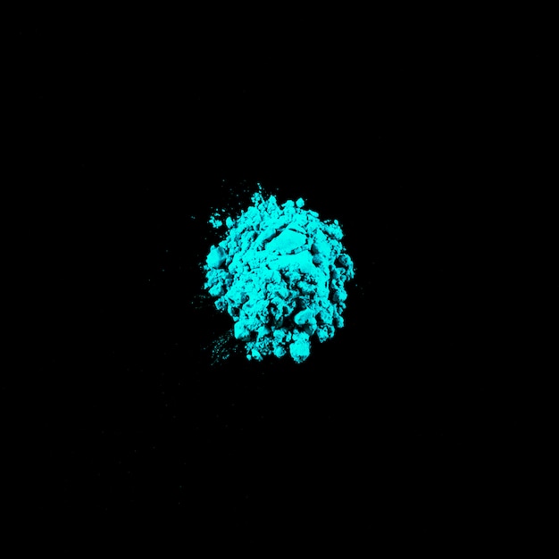 Free photo top view of turquoise holi powder on middle of black background