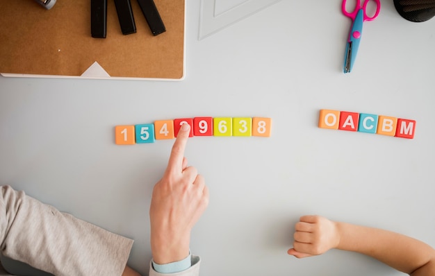 Free photo top view of tutor teaching child at desk about numbers and letters