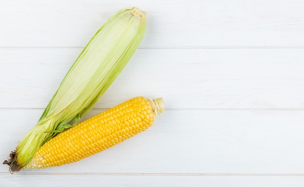 Top view of uncooked and cooked corns on left side and wood with copy space