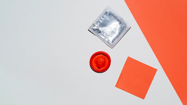 Top view unwrapped red condom on white background