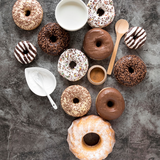 Free photo top view of variety of donuts with milk and powdered sugar