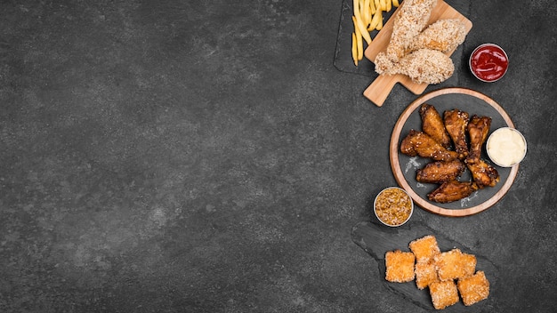 Top view of variety of fried chicken with french fries and copy space