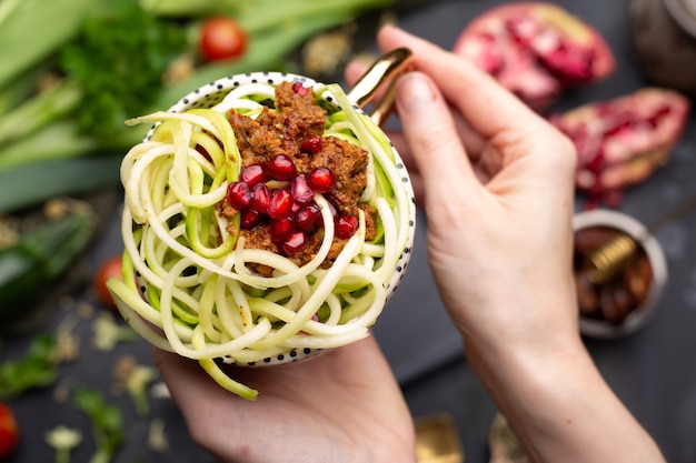 Top view of a vegan meal with spiralized zucchini, tomato sauce and pomegranates in the cup