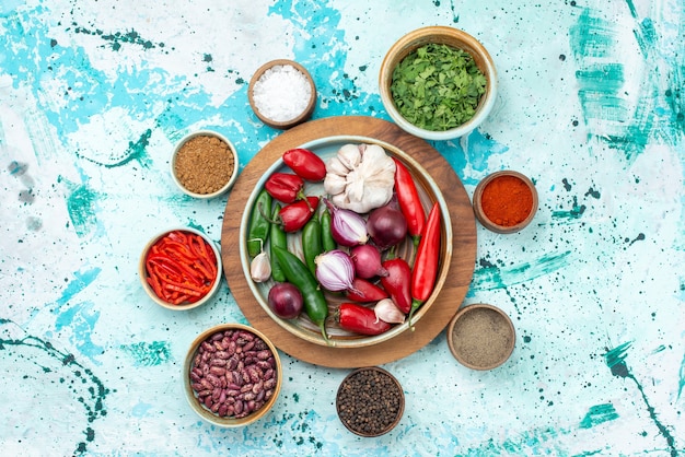 Top view vegetable composition peppers onions garlics and greens on the light-blue table food meal salad ingredient