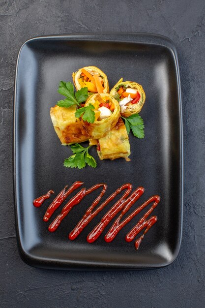 Top view vegetable pate rolls inside black plate on dark surface