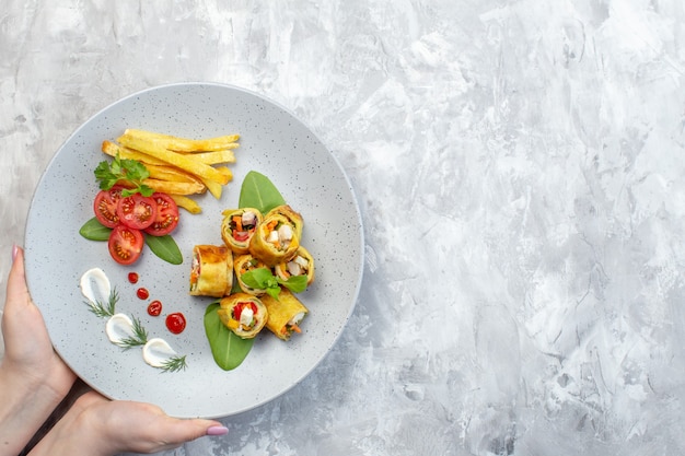 Top view vegetable pate rolls with tomatoes and french fries inside plate on white surface