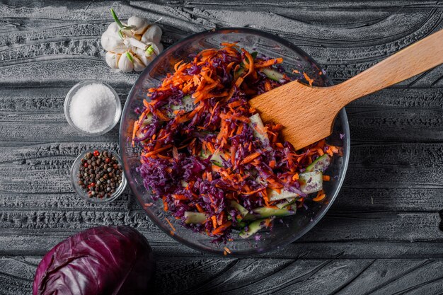 Top view vegetable salad in bowl with with spices on dark wooden table