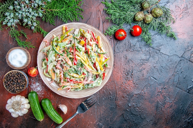 Free Photo top view vegetable salad on plate fork tomatoes pine branches cucumbers garlic on dark red table free place