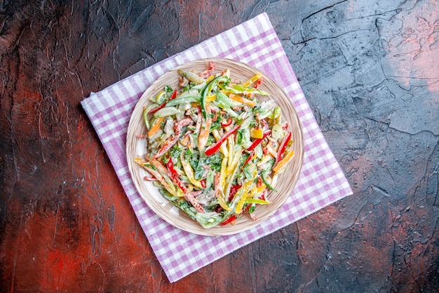 Free Photo top view vegetable salad on plate on tablecloth on dark red table copy place