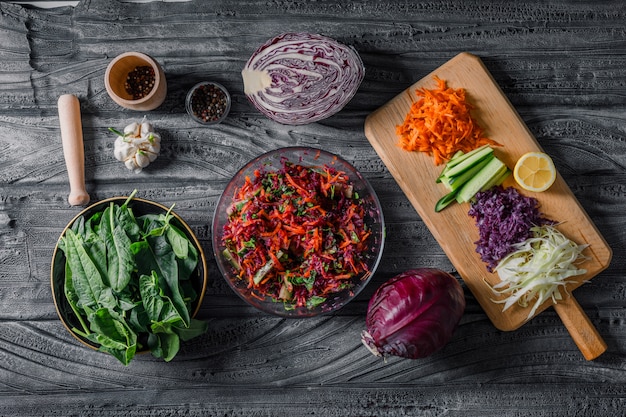 Top view vegetable salad with sliced vegetables, greens and spices on dark wooden background. horizontal