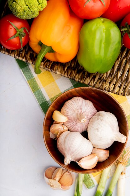 Top view of vegetables as garlic, peppers and tomatoes on wicker basket