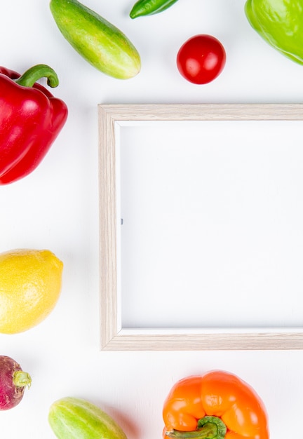 Free photo top view of vegetables as pepper cucumber radish tomato with frame on white with copy space