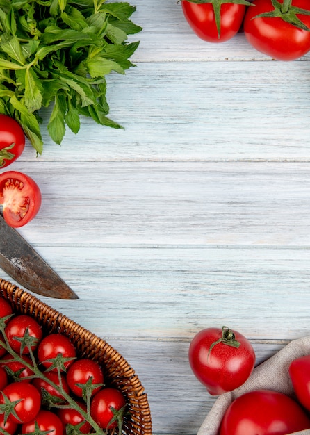 Top view of vegetables as tomato green mint leaves with knife on wooden surface with copy space