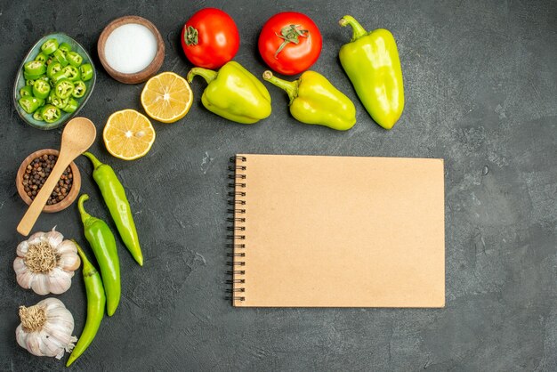 Top view vegetables composition tomatoes bell-peppers and garlics on dark background