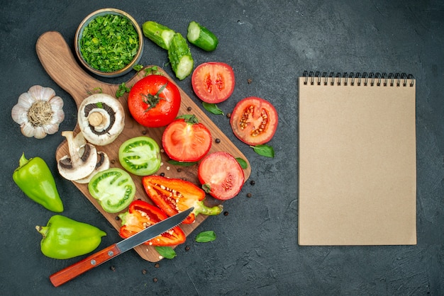 Top view vegetables cucumbers green and red tomatoes bell peppers knife on cutting board