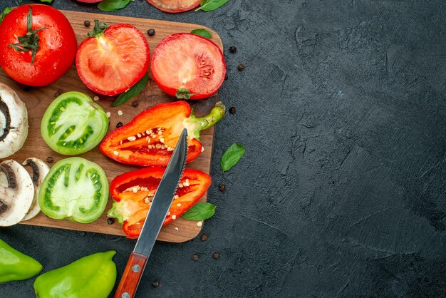 Top view vegetables cucumbers green tomatoes bell peppers on chopping board