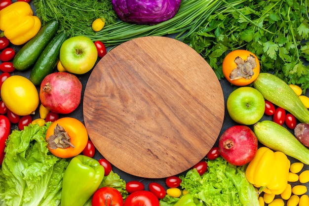 Free Photo top view vegetables and fruits lettuce tomatoes cucumber dill cherry tomatoes zucchini green onion parsley pomegranate persimmon apple round wood board on center