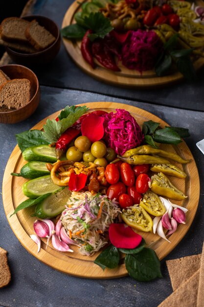 A top view vegetables sliced and whole cucumbers lettuce on the brown wooden desk along with bread loafs on the grey desk vitamine plants