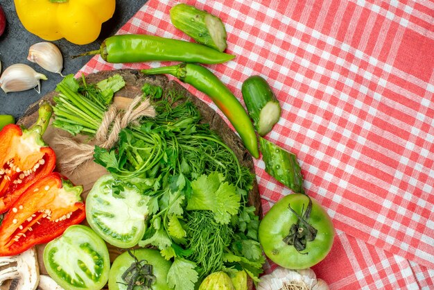 Top view vegetables tomatoes red bell peppers greens on wood board