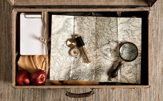 Free photo top view vintage suitcase with map and magnifying glass