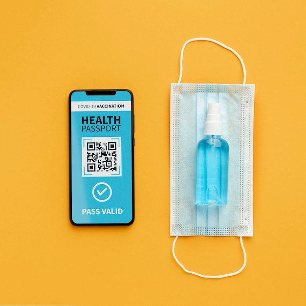 Top view of virtual health passport on smartphone with medical mask and hand sanitizer