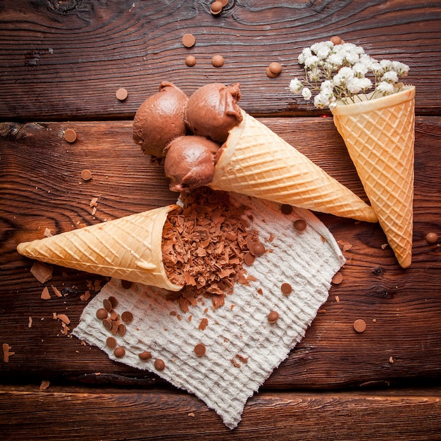 Free photo top view waffle cones with chocolate ice-cream and gypsophila and chocolate chips in rag napkins