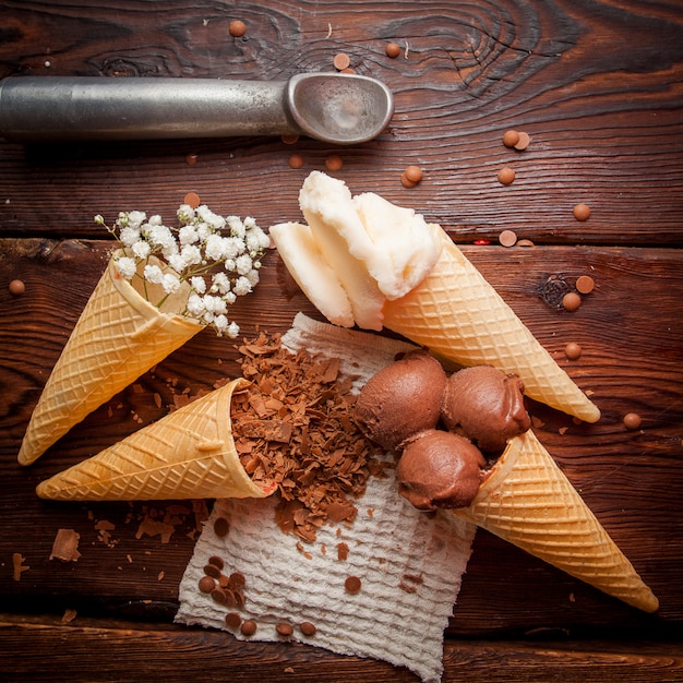 Free photo top view waffle cones with chocolate ice-cream and vanilla ice cream and chocolate chips and ice cream spoon in rag napkins