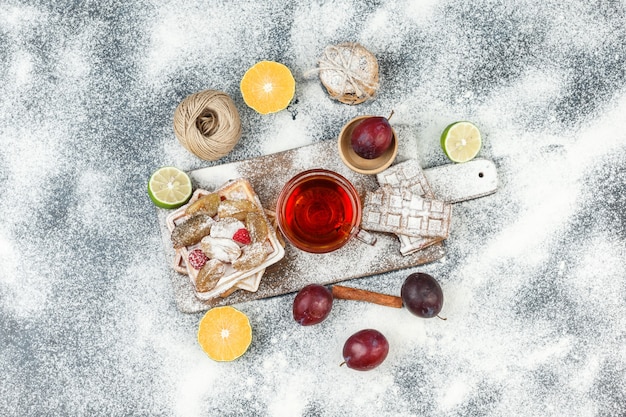 Free photo top view waffles and rice wafers with citrus fruits,cinnamon and cookies on dark grey marble surface. horizontal