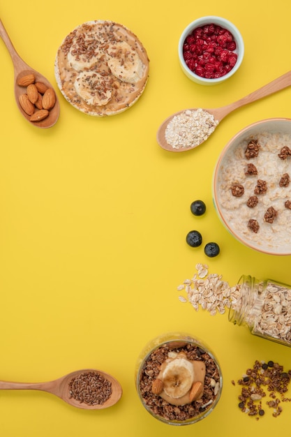 Top view of walnut milk oatmeal banana crispbread snack and banana walnut almond smoothie with red currant blackthorn spoons full of chia seeds and almonds on yellow background