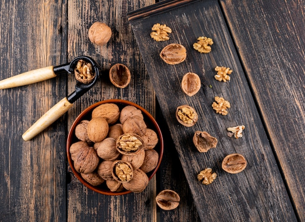 Top view walnuts in bowl and nutcracker on wooden  horizontal