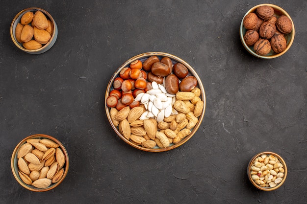 Top view of walnuts, peanuts, and other nuts on dark surface