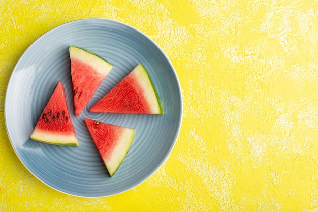 Free Photo top view of watermelon slices inside blue plate on the yellow surface