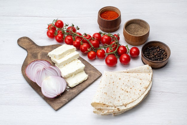 A top view white cheese with onions and fresh red tomatoes on the light surface