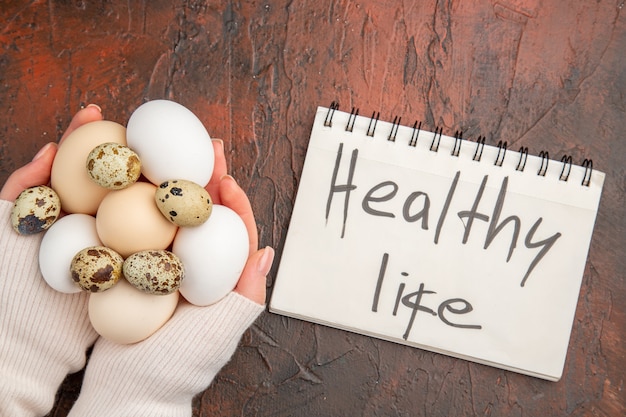 Free Photo top view white chicken eggs in female hands on dark table