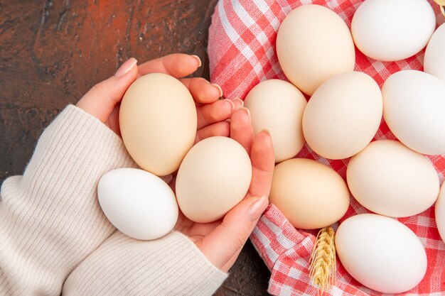 Top view white chicken eggs inside basket with towel on dark table