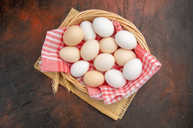 Top view white chicken eggs inside basket with towel on dark table