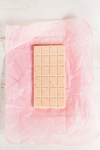 Free photo top view of white chocolate bar on pink paper wrapper