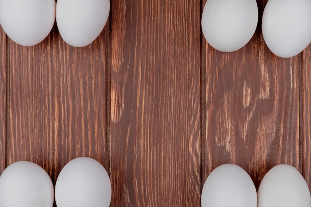 Free photo top view of white fresh chicken eggs arranged in different sides on a wooden background with copy space