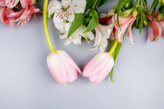 Top view of white and pink color alstroemeria flowers with pink tulips on white table