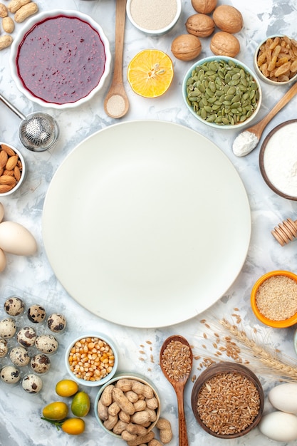 Top view white plate bowls with almonds corn seeds peanuts wheat grains sesame seeds jam eggs walnuts quail eggs