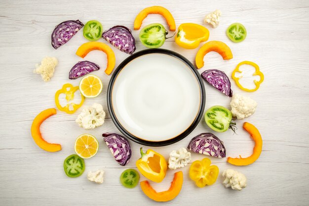 Top view white platter cut vegetables on white wooden table